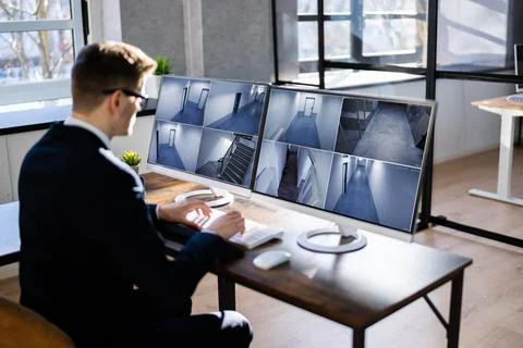 Security System Operator Looking At CCTV Camera Footage Foto stock