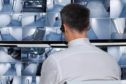 Security System Operator Looking At CCTV Footage At Desk Foto stock