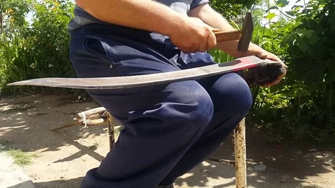 A sedentary old man sharpens his scythe with a hammer 動画素材 113552192