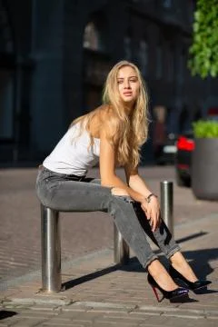 Seductive blonde model with long hair wearing jeans and t shirt posing at the Stock Photos