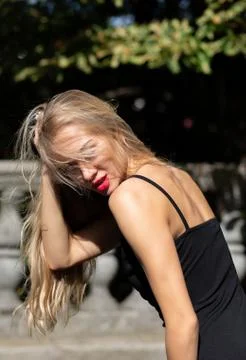 Seductive blonde model with long hair and red lips wearing black dress, posin Stock Photos