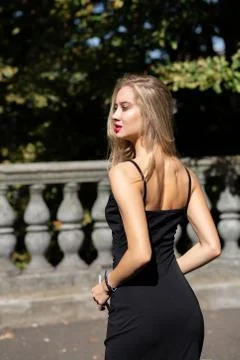Seductive blonde model with long hair wearing black dress, posing near the ba Stock Photos