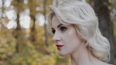 Seductive blonde with red lips puts on sunglasses and looks straight in park Stock Footage 124731118