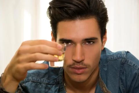Seductive handsome young man sitting drinking Stock Photos