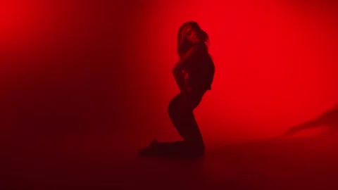 Seductive lady performing strip plastic on knees at dark red light studio. Wide Stock Footage 152026986