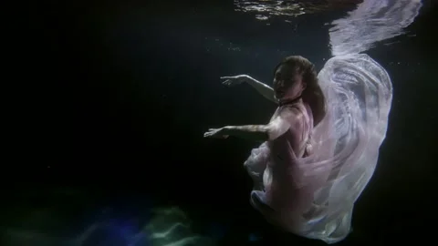 Seductive woman is floating in depth of dark swimming pool, romantic flowing Video stock 167279898