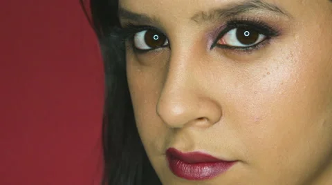 Seductive Woman looking directly into the camera on a red background Stock Footage 63861381