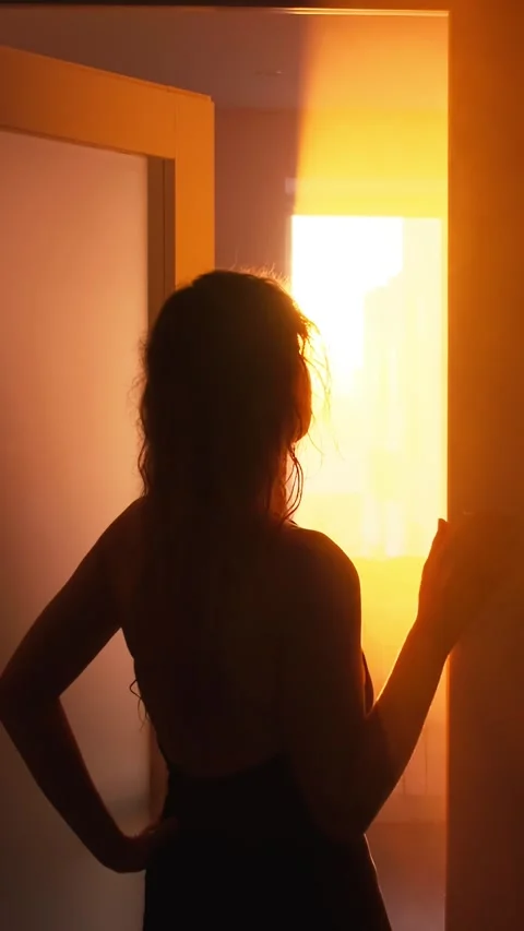 Seductive young beautiful woman opens door with sun light rays, black silhouette Stock Footage 332209658