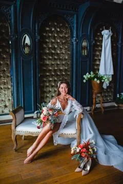 Seductive young bride posing with gorgeous bridal bouquet on a sofa Stock Photos