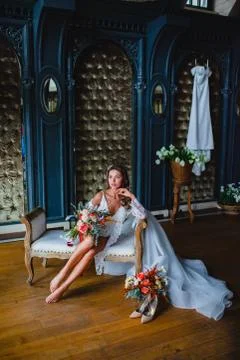 Seductive young bride posing with gorgeous bridal bouquet on a sofa Stock Photos