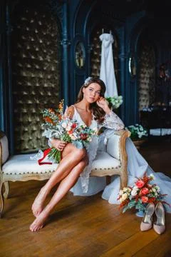Seductive young bride posing with gorgeous bridal bouquet in the hotel room Stock Photos