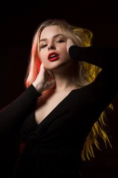 Seductive young lady with bright makeup and long wavy hair posing over a blac Stock Photos