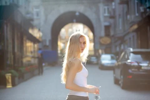 Seductive young model with long hair holding glasses, posing at the passage i Stock Photos