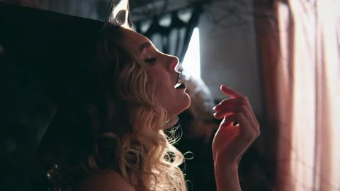 Seductive young witch with curly blonde hair and black lipstick licking her 動画素材 330786486