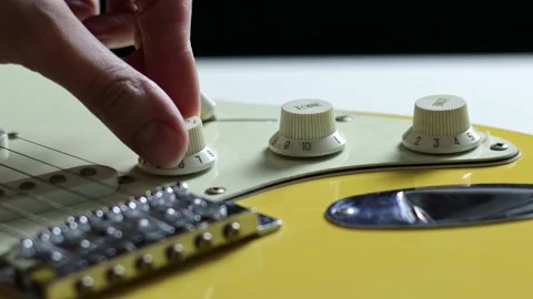 See the volume knob on a yellow electric guitar being rotated in a seamless Stock Footage