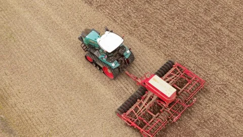 Seed drill and powerful tractor working across dry arable land. Precision Stock Footage 346604885