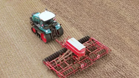 Seed drill working behind tracked tractor across dry crop stubble. Agricultural Stock Footage 345501196