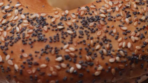 Seeded bagel bun rotating in macro textured seamless loop for culinary visual Stock Footage 323237616