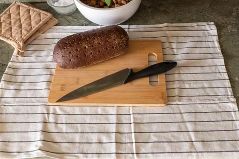 Seeded rye bread loaf and knife on a wooden cutting board Stock Photos