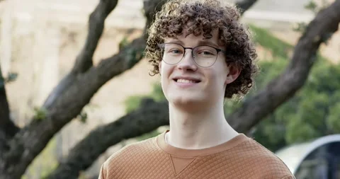 Seeing camera, man wearing glasses, tan pullover turning head and smiling as car Stock Footage 340968867