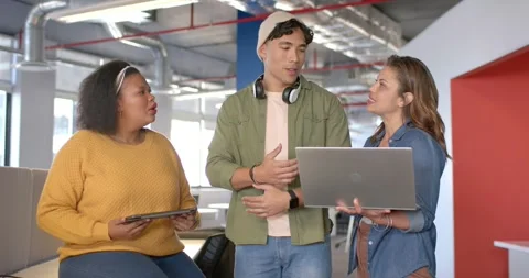 Seeing tablet mockup in office, diverse coworkers leaning at laptop refining Stock Footage 317640307