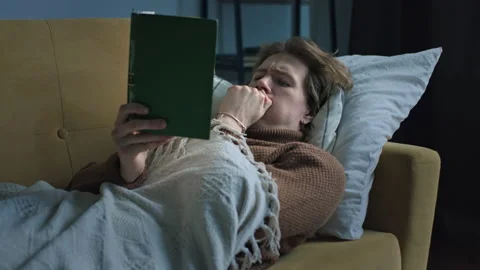 Seek handsome guy is reading book lying at the sofa under the blanket Stock Footage 146309282