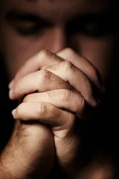 Seeking divine intervention. Hands clasped in prayer in front of a blurred face. Stock Photos