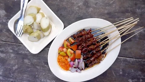 Seen from above beef satay, chili sauce and lontong on the dining table Stock Footage 273040892