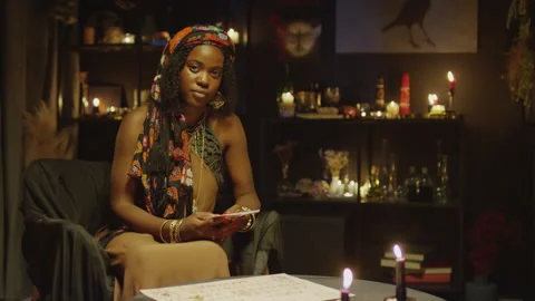 Seer Sitting with Tarot Cards at Table and Looking at Camera Stock Footage 247637423