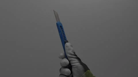 Segment knife in the hand on a gray background. Stockbeeldmateriaal 265597389