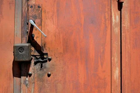 Segment of rusty garage doors with padlock and handle.	 Stock Photos