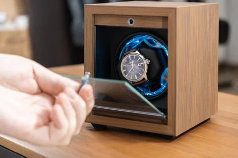 Seiko automatic wristwatch rotating in a sleek wooden winder box with blue LED Stock Photos