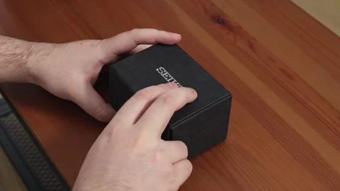 Seiko watch box opening by hands to reveal a luxury timepiece on a wooden table Stock Footage 346464750