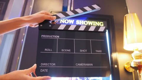 Select focus of Clapper board or movie slate with hand in front of now showin Stock Photos