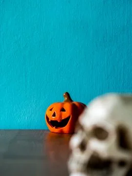 Select focus for halloween pumpkin head behind of skull on the wooden table. Stock Photos