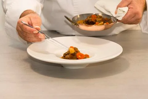 Select focus of a plate with beef stew being carefully arranged with pliers b Stock Photos