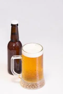 Select focus of a tempting cold mug of beer with an out of focus beer bottle  Stock Photos