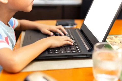 Selected focus childrens hand using laptop keyboard playing on dinner table. Stock Photos