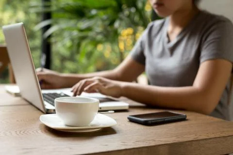 Selected focus cup of coffee on the table with young woman stude Stock Photos
