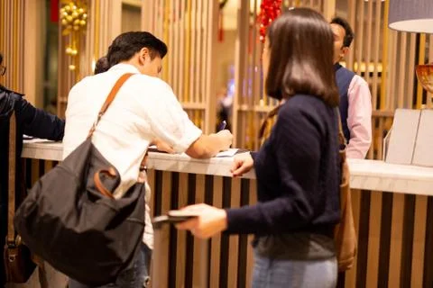 Selected focus man signing document check in at hotel with wife in foreground. Stock Photos