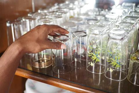Selecting glasses from a shelf in a kitchen Stock Photos
