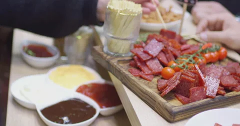 Selecting salami slices using toothpicks at a charcuterie board Stock Footage 302355530