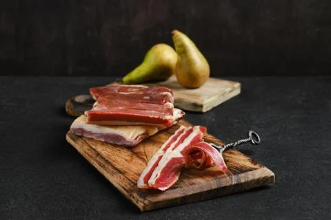 Selection of cured duck breasts and pears arranged on wooden cutting boards.. Foto stock