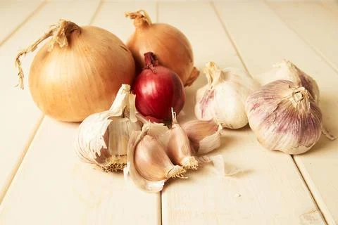 Selection of different common, red and garlic onions on white wooden table Stock Photos