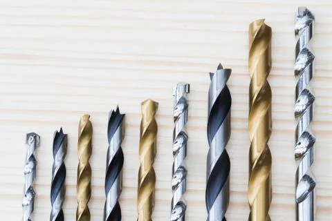 Selection Of Drill Bits Arranged In Ascending Size On Wooden Background Stock Photos