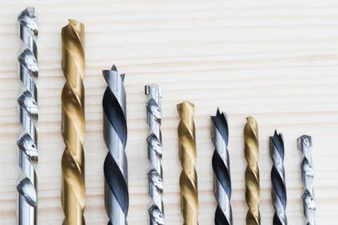 Selection Of Drill Bits Arranged In Descending Size On Wooden Background Stock Photos