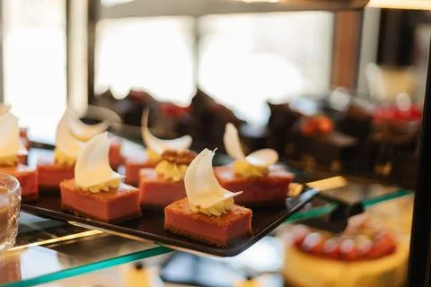 A selection of elegant mousse desserts sits on a glass display case, showcasi Stock Photos