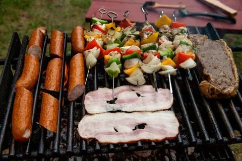 Selection of meat grilling over the coals with spicy sausages, bacon and chic Stock Photos