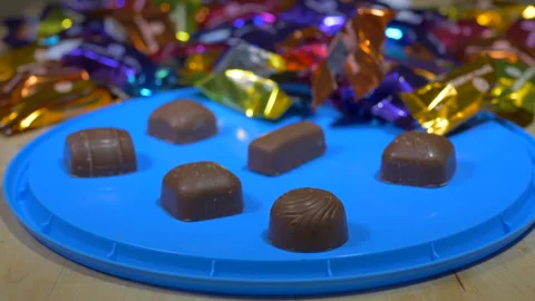 Selection of milk chocolates – some wrapped, others unwrapped on a lid. Stock Footage 145582096
