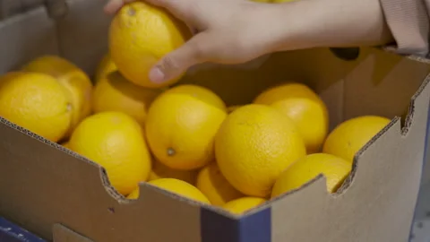 A selection of oranges in a supermarket, a woman's hand picking up fresh orange Stock Footage 228846997